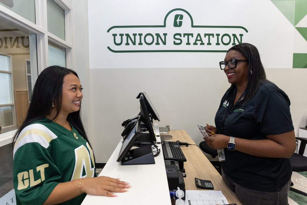 student talking to Union Station worker behind desk.