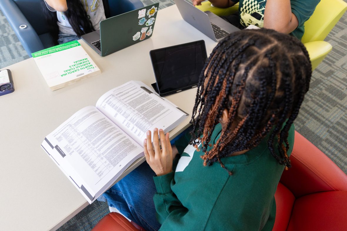 Overhead shot of student looking at textbook on table.