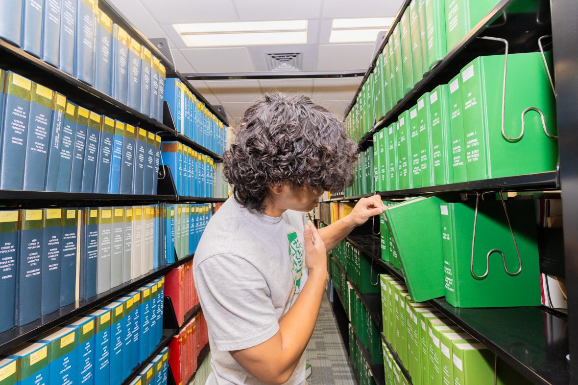 Student looking at a bookshelf.