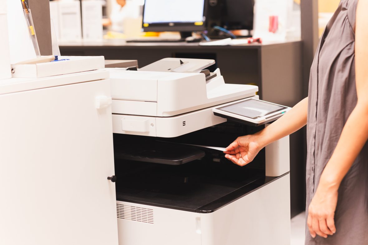 Hand pulling paper from printer.