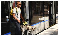 Photo of a man who is blind, with his service dog, exiting light rail car