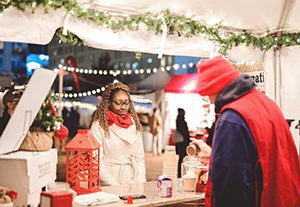 Photo of man in red toboggan serving hot cocoa to woman wearing red scarf