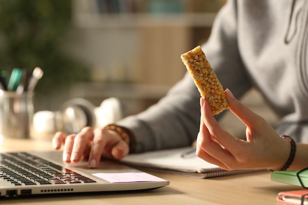 Student typing at computer with snack