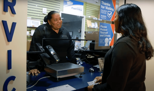 Mail & Package Services staff member helps customer at front counter