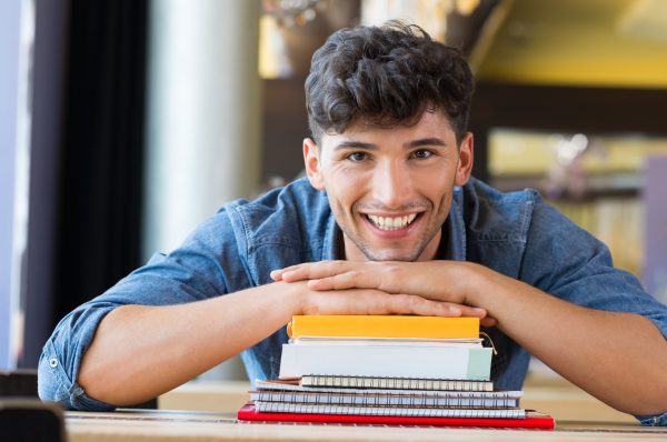 Student with books smiles at viewer