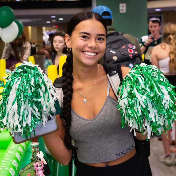 smiling female student poses with green pom poms in Barnes & Noble Charlotte