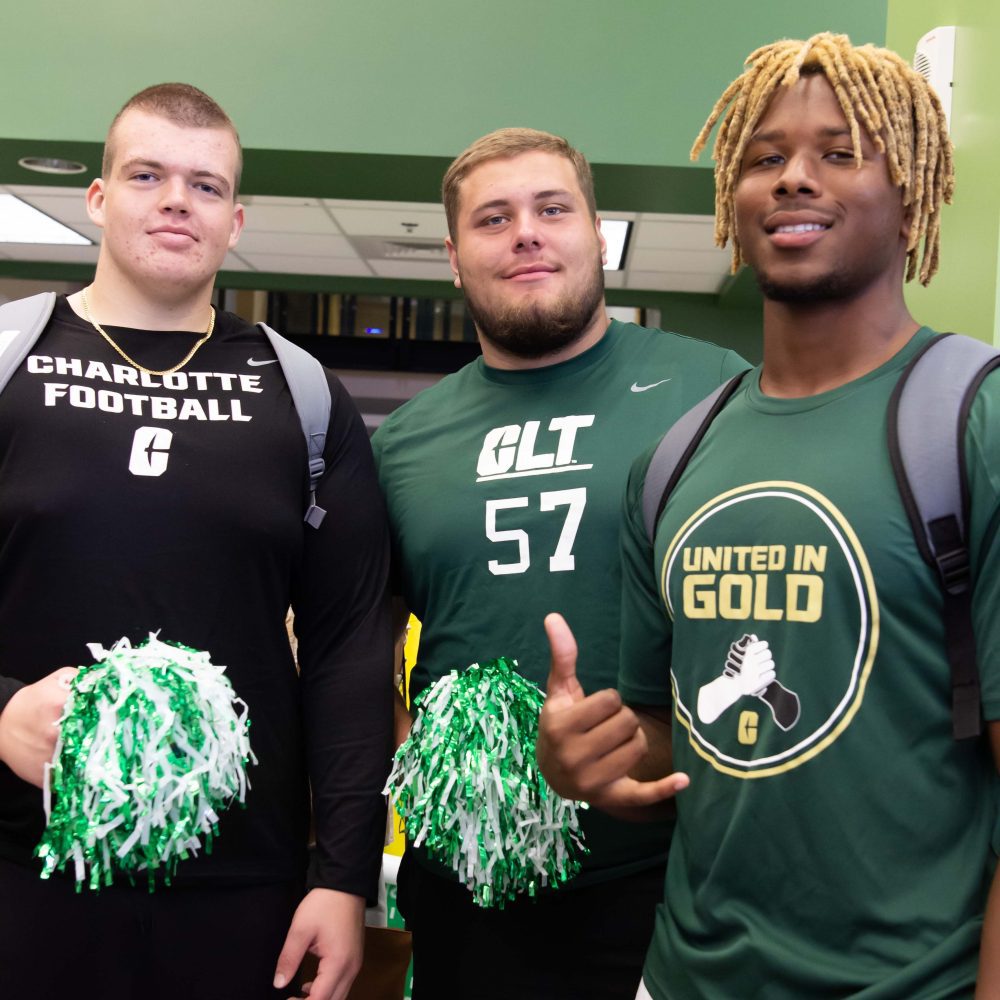 Three student athletes pose with pom poms in in Charlotte Barnes & Noble