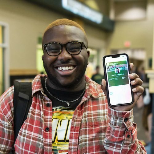 Student holding mobile ID and smiling at camera