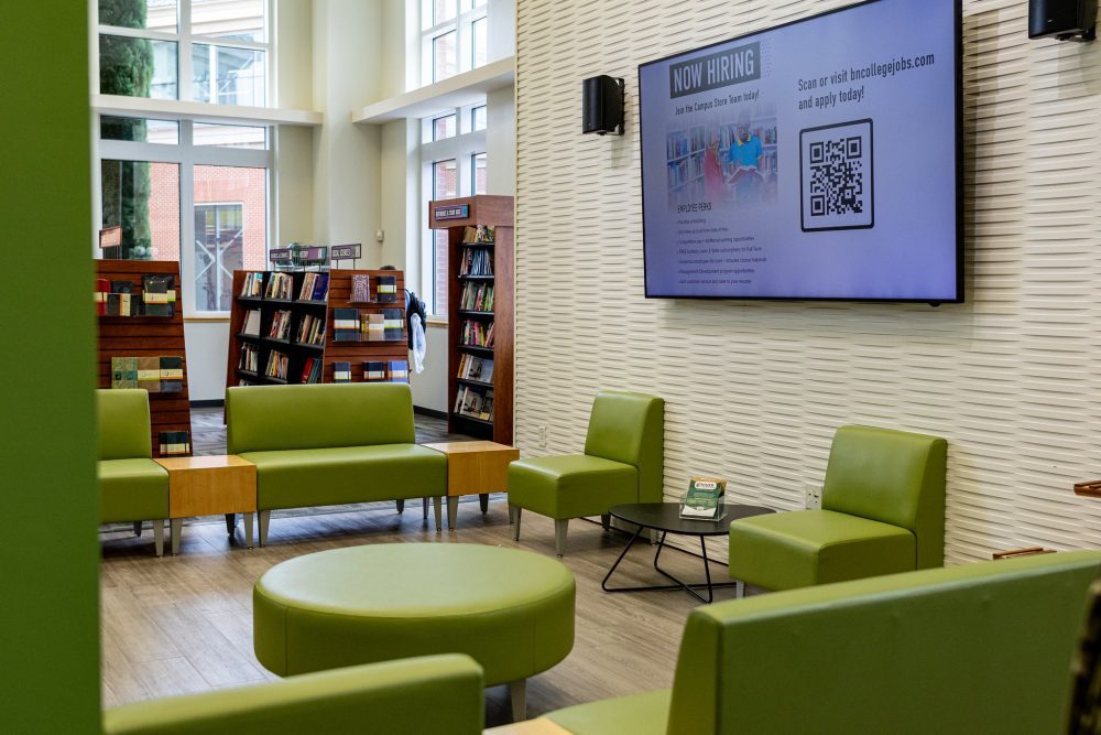 Light green chairs arranged to face each other with a flat-screen tv and bookshelves in the background.