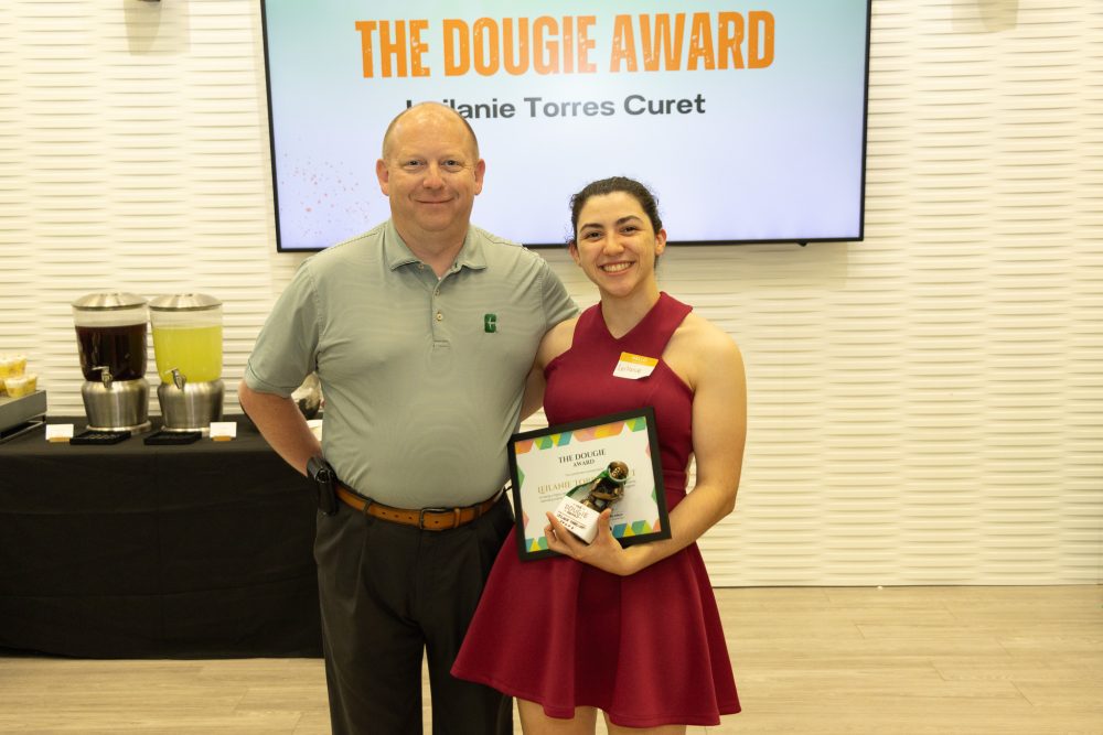 Leilanie Torres Curet stands with AVC of Business Services, Doug Lape, holding her Dougie Award certificate and trophy.