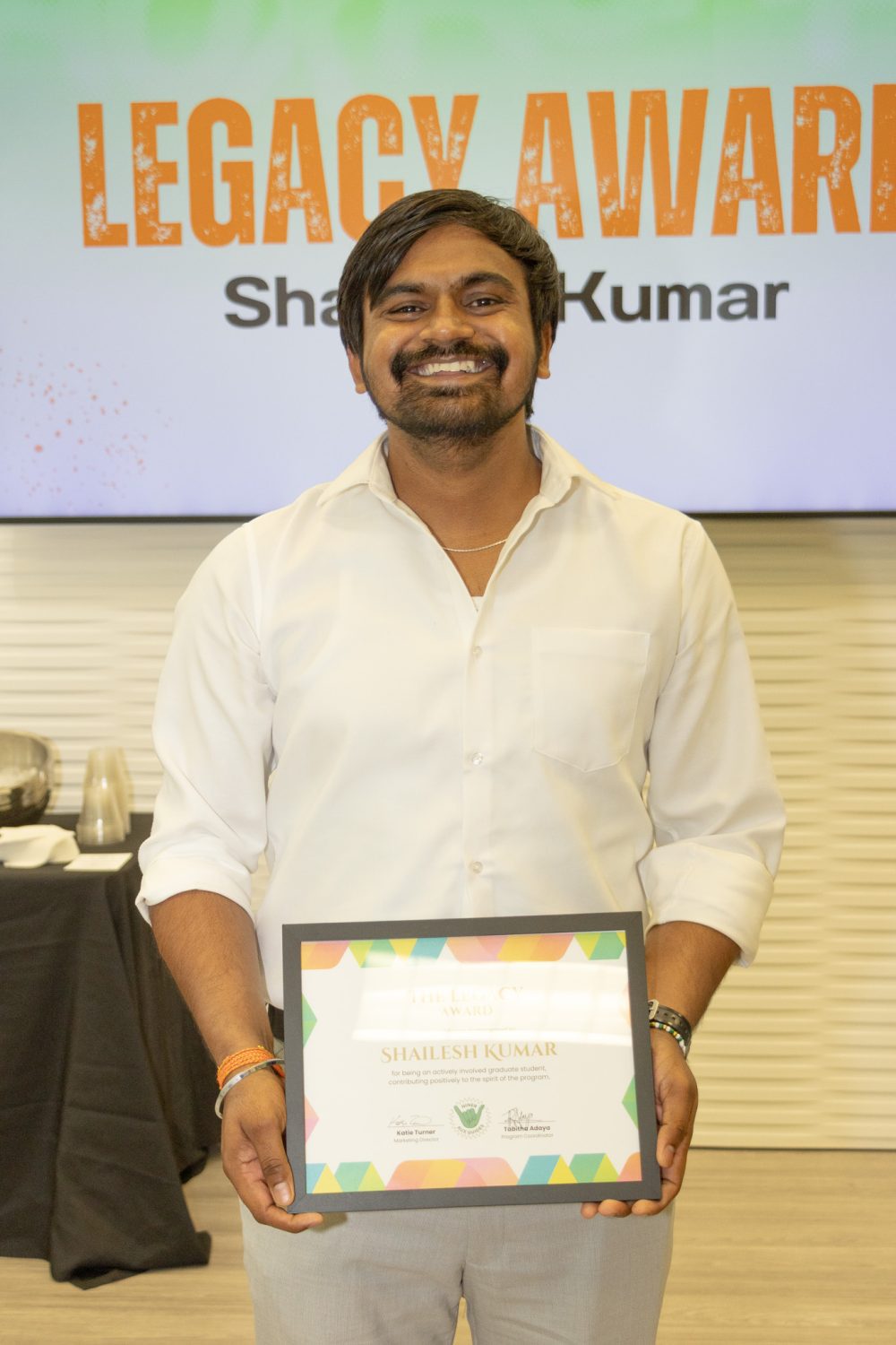 Shailesh Kumar poses smiling and holding the Legacy Award certificate.