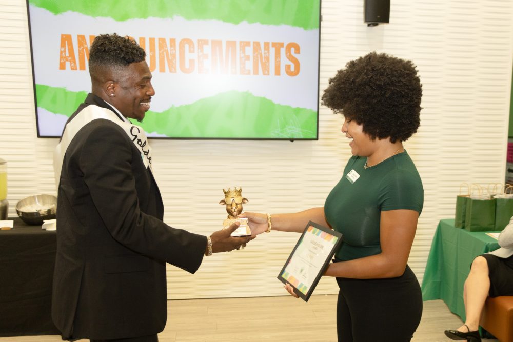 Niner Aux Guide co-lead Natalia Harris hands GOAT trophy and certificate to S.L. Ivey.
