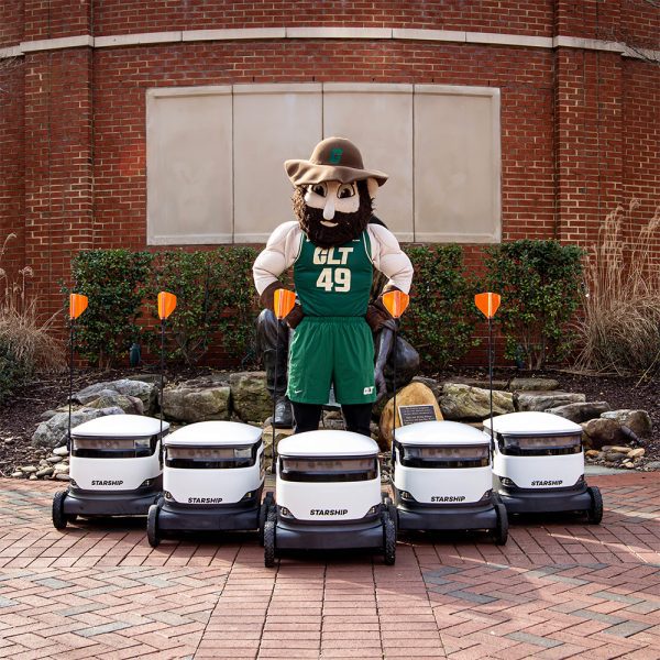 fleet of starship robots pose in front of proud Norm mascot outside the SAC