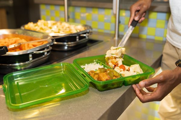 Student fills an OZZI container with food from the dining hall