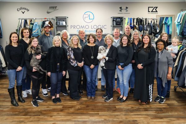 18 men and women from the Promo Logic team pose for a group picture along with two dogs and a baby