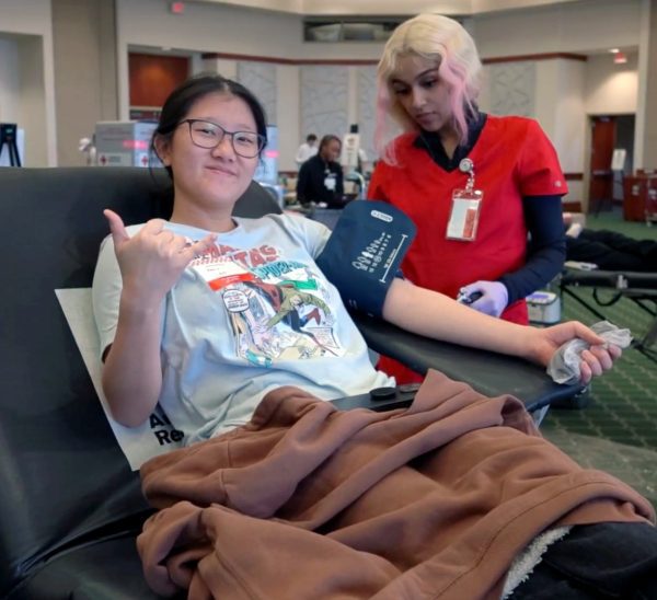 Red Cross technician checks student's blood pressure before getting her blood drawn
