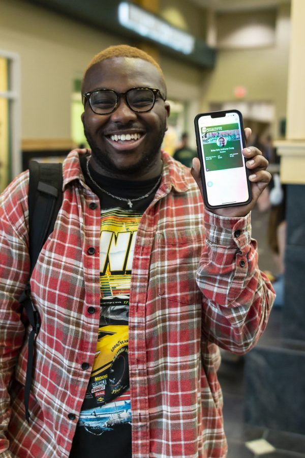 smiling University student holds up their smart phone showing their 49er mobile ID on the screen