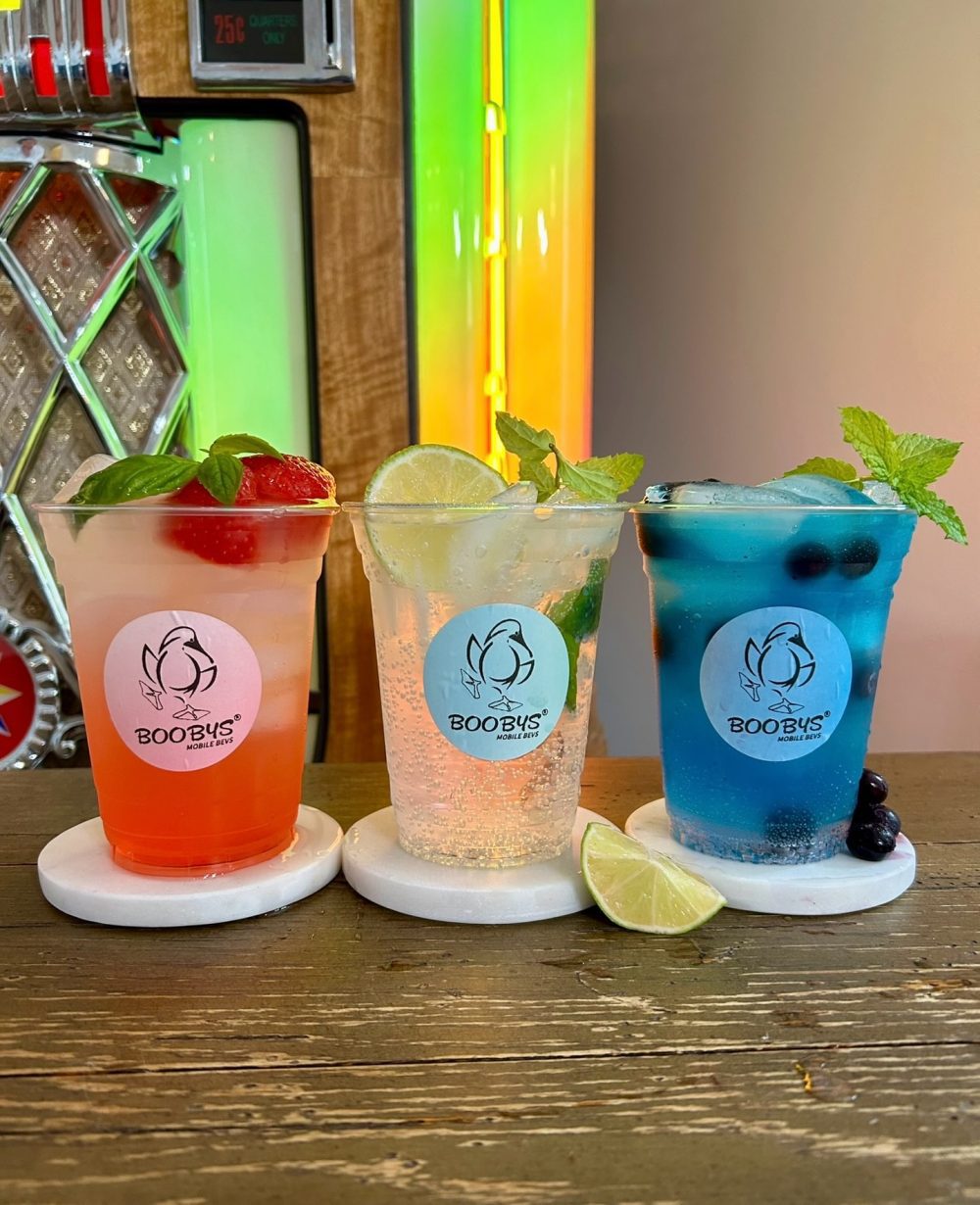 three colorful mocktails with fruit and mint toppings and Boobys Mobile Bevs logo labels